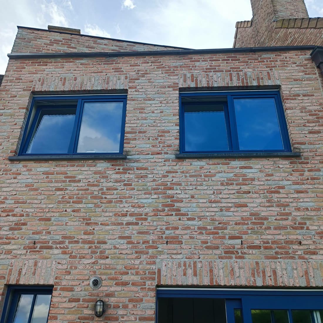 Bakstenen gevel met nieuwe zwarte ramen — VDC Construct, West-Vlaanderen